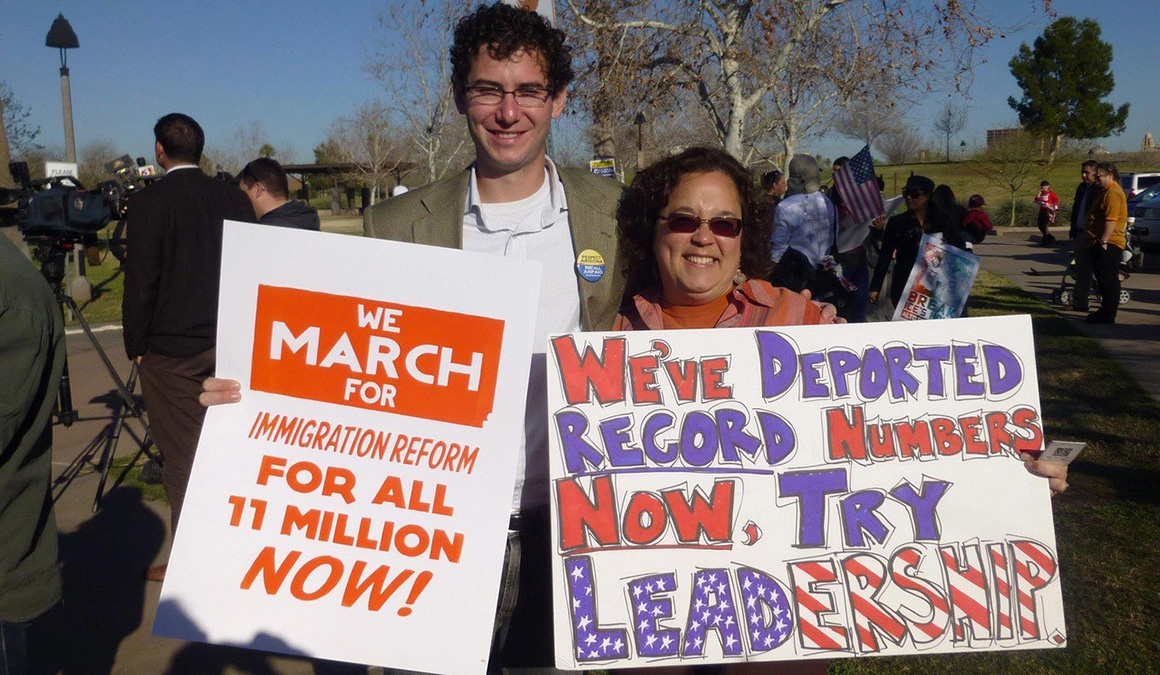 Jillian Kong-Sivert ’91 and her former associate, Daniel Lubarsky-Ford ’08, hold up signs for immigration reform.